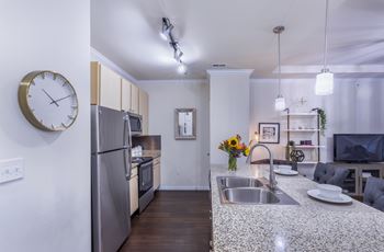 A modern kitchen with a granite countertop and stainless steel appliances.